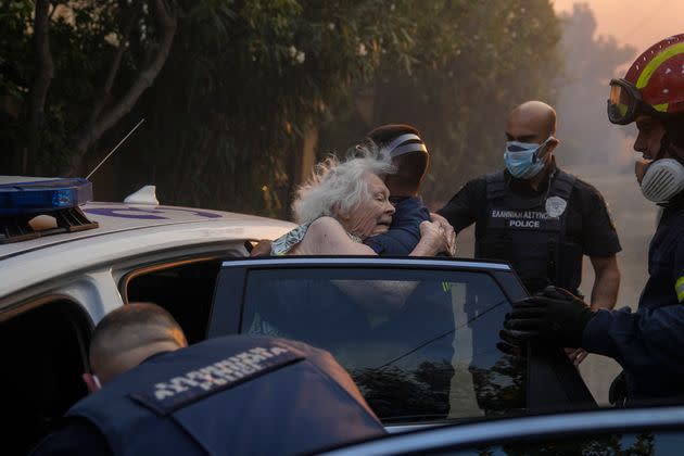 Firefighters and policemen evacuate an elderly woman from her house in Penteli, Greece, on Tuesday, July 19, 2022. (AP Photo/Thanassis Stavrakis) (Photo: via Associated Press)