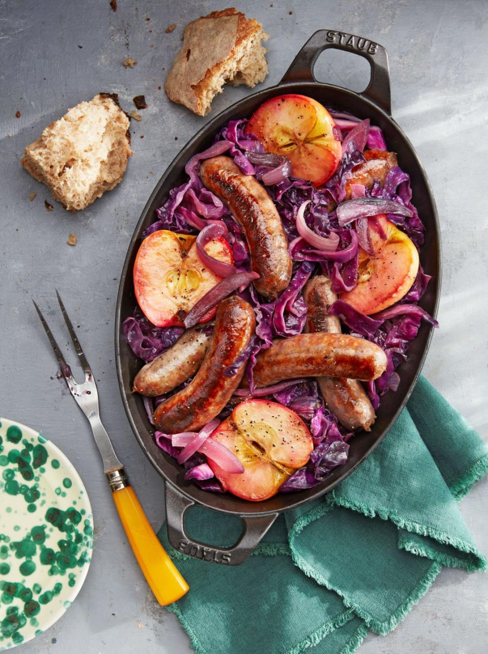 seared sausage with cabbage and pink lady apples in an oval cast iron dish