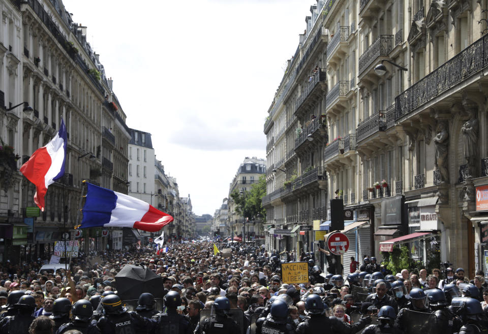 Protestors march waving French flags during a demonstration in Paris, France, Saturday, July 31, 2021. Demonstrators gathered in several cities in France on Saturday to protest against the COVID-19 pass, which grants vaccinated individuals greater ease of access to venues. (AP Photo/Adrienne Surprenant)