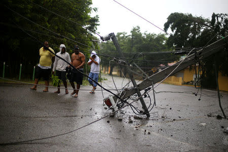 Locals walk past a fallen power pole as Hurricane Irma moves off the northern coast of the Dominican Republic, in Puerto Plata, Dominican Republic September 7, 2017. REUTERS/Ivan Alvarado