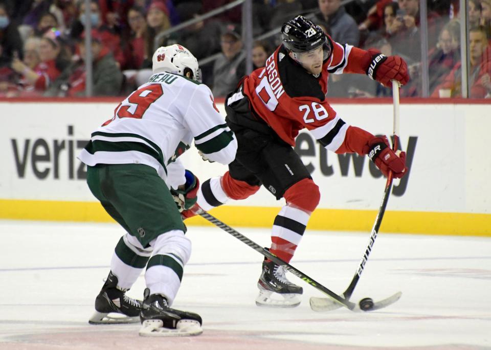 New Jersey Devils defenseman Damon Severson (28) takes a shot as Minnesota Wild center Frederick Gaudreau (89) defends during the first period of an NHL hockey game Wednesday, Nov. 24, 2021, in Newark.