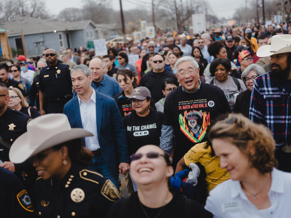 El alcalde de San Antonio, Ron Nirenberg, en el centro a la izquierda con una chamarra azul, y Peter Sakai, el juez del condado de Béxar, en el centro a la derecha, asisten al desfile del Día de Martin Luther King, en San Antonio, el 16 de enero de 2023. (Christopher Lee/The New York Times)