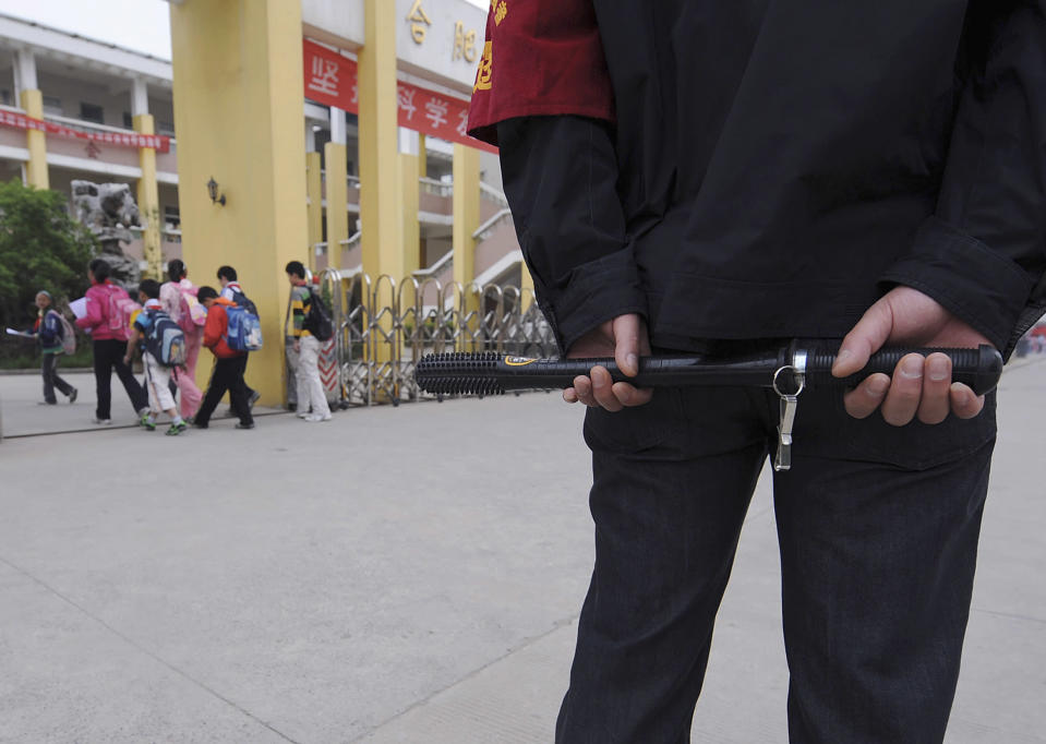 A security guard equipped with police baton stands at the entrance of a primary school in Hefei