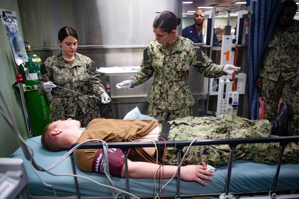 Hospitalman Apprentice Nikki Capozello, left, and Hospital Corpsman 3rd Class Rebekah Perkins practice running an IV line during a medical response team training aboard the hospital ship USNS Comfort.