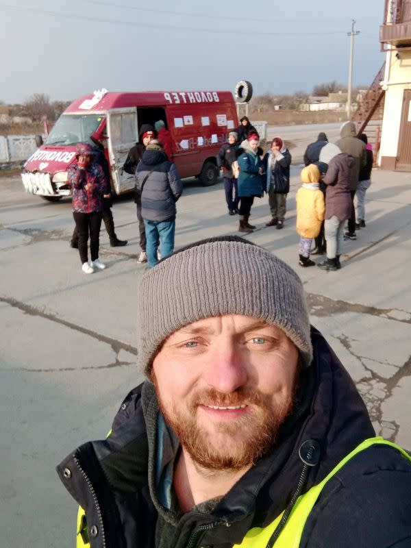 Mykhailo Puryshev poses for a selfie photo in front of a car as he evacuates people fleeing Russia's invasion of Ukraine, in Zaporizhzhia