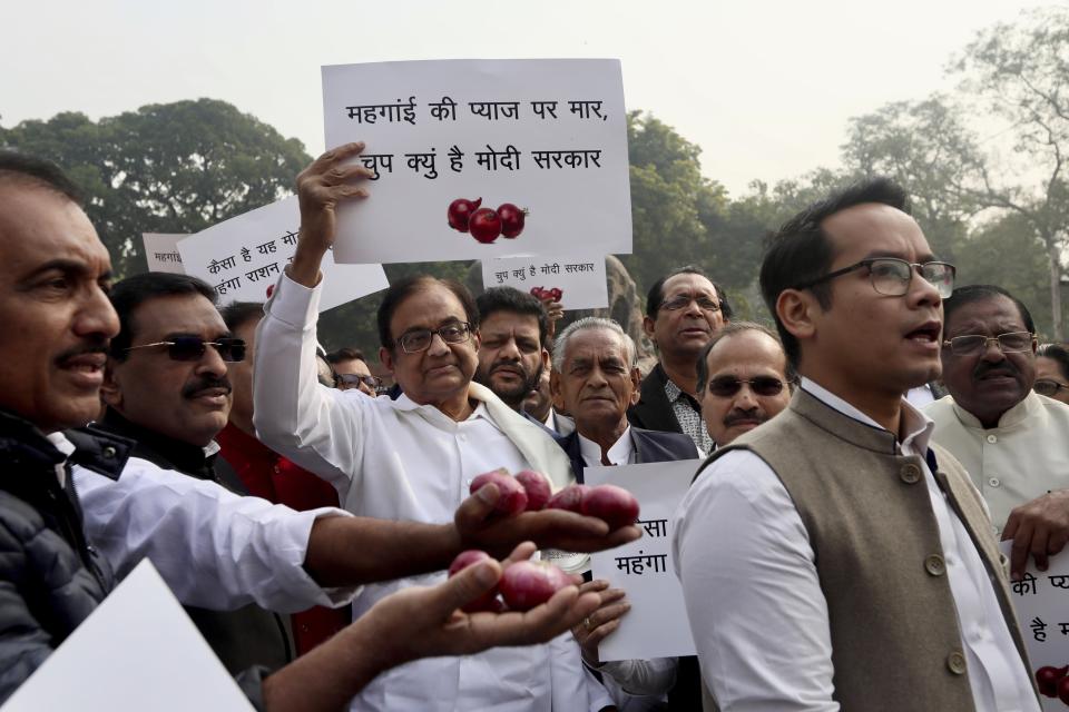 Indian lawmaker and former Finance Minister Palaniappan Chidambaram, center, holds a placard that reads "Why is the Modi government silent on the rise of onion prices, participates in a protest against the rise in onion prices, outside the Indian parliament in New Delhi, India, Thursday, Dec. 5, 2019. The former Indian finance minister just released on bail in a bribery case has joined a protest of the government’s economic policies, which are being blamed for India’s slowest economic growth in six years. (AP Photo/Manish Swarup)