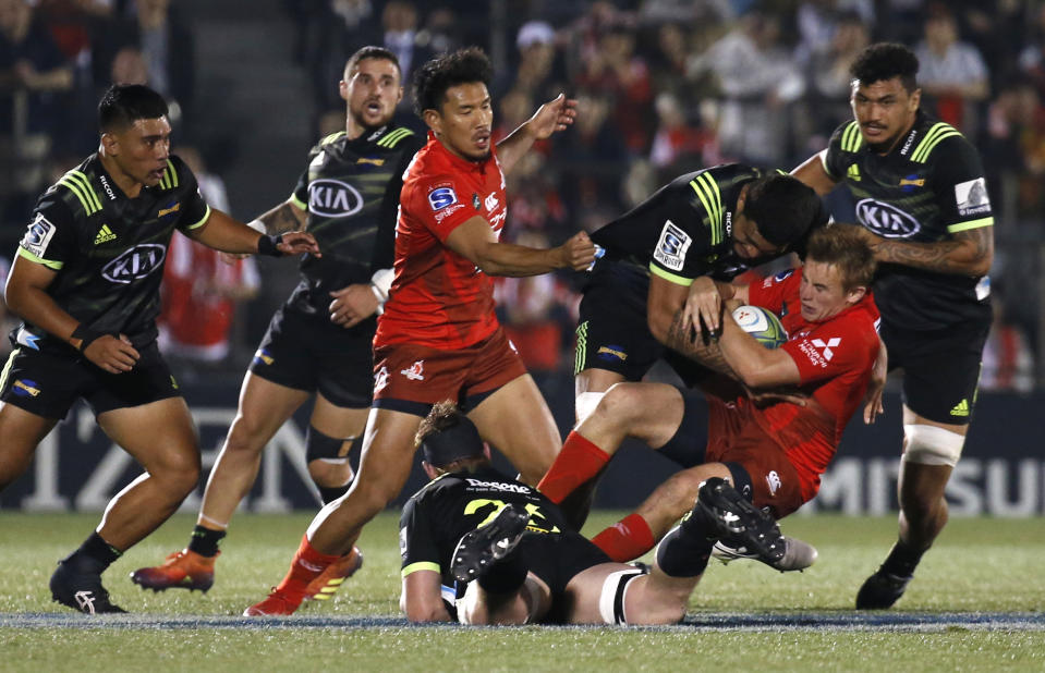 Sunwolves Hayden Parker, second from right, is tackled by Hurricanes defense during the Super Rugby game between the Hurricanes and Sunwolves in Tokyo, Friday, April 19, 2019. (AP Photo/Shuji Kajiyama)