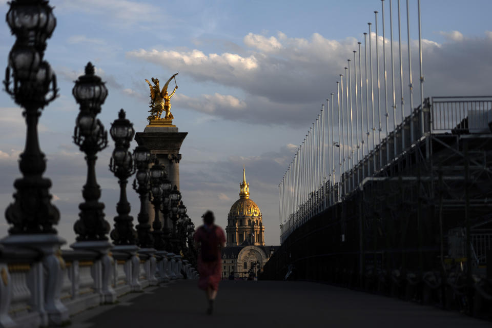 El sol se pone frente al Hotel des Invalides con gradas de espectadores alineadas en el puente Alejandro III sobre el río Sena, el viernes 19 de julio de 2024, en París, antes de los Juegos Olímpicos de Verano de 2024. (Foto AP/David Goldman)