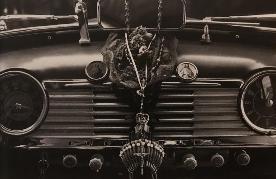 Religious symbols are displayed amid knobs and dials on the dashboard of a 1950s-era Chevy.