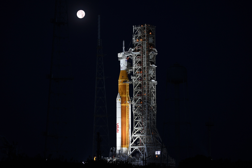 The full moon sets behind the Space Launch System moon rocket June 15 at the Kennedy Space Center. / Credit: William Harwood/CBS News