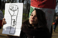 Lebanese protester holds a paper reading "Revolution" during a gathering outside of the French foreign ministry in Paris, Wednesday, Dec. 11, 2019, to denounce a closed-door meeting of diplomats from several countries on aid to Lebanon. The Middle Eastern country is facing a political and economic crisis, and the international group is discussing conditions for global assistance to help ease Lebanon's financial woes.(AP Photo/Francois Mori)