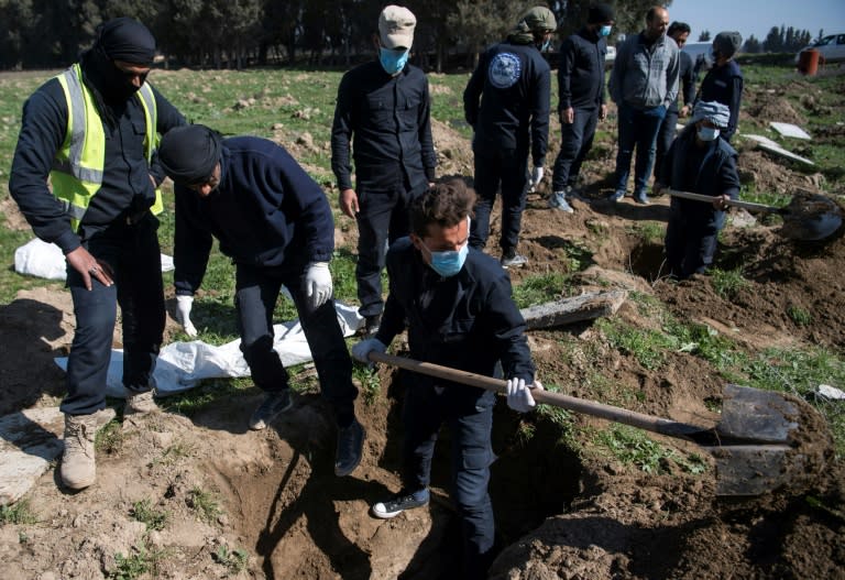 Civil defence workers excavate the site of a mass grave near the northern Syrian city of Raqa which may also contain the bodies of some foreigners imprisoned by Islamic State jihadists, whose fates remain unknown
