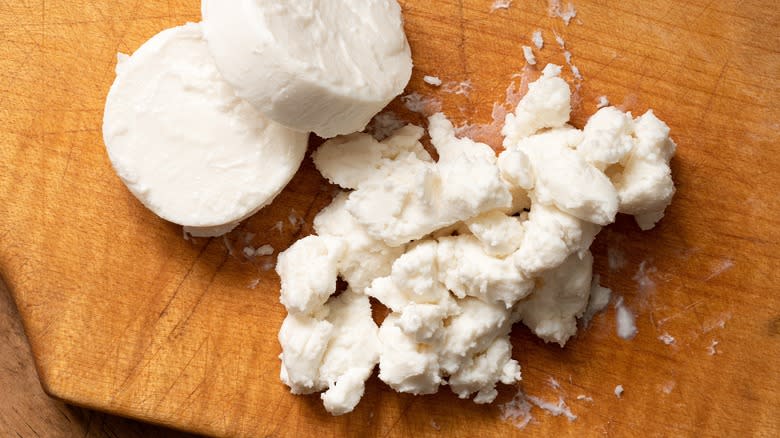 Goat cheese crumbled on a wooden cutting board
