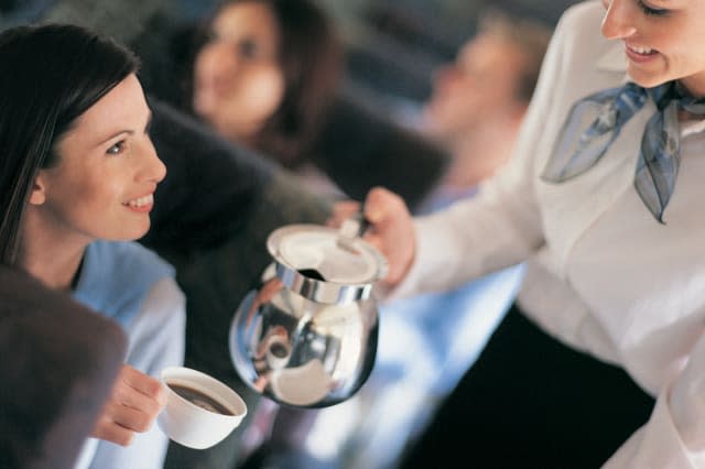 Female Passenger Being Served Coffee By An Air Stewardess