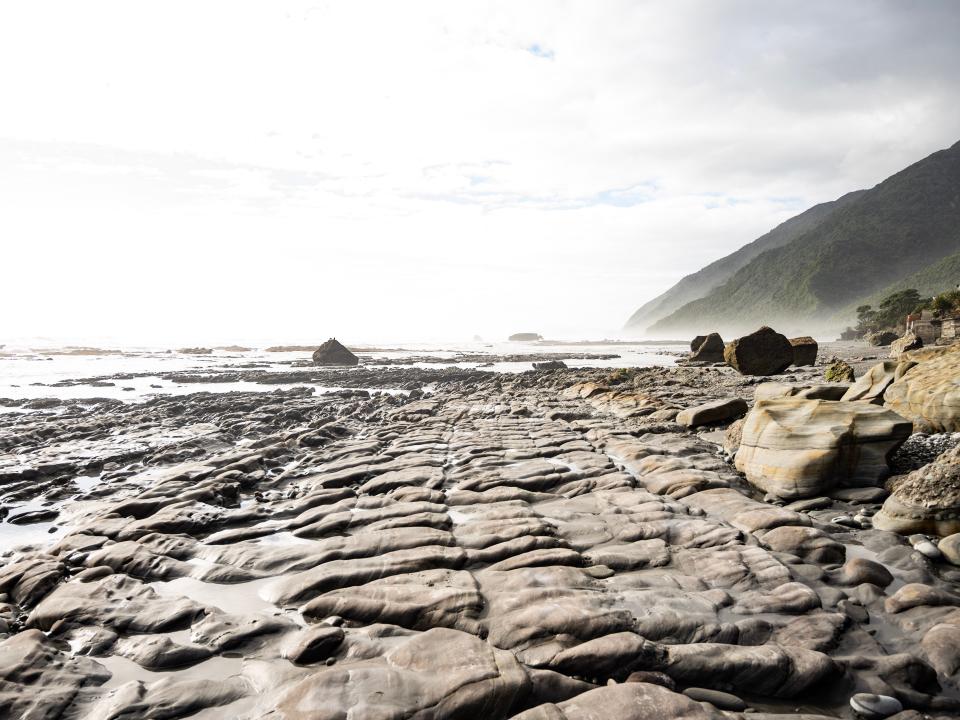 A coastal beach area at low tide to reveal layered rocks.