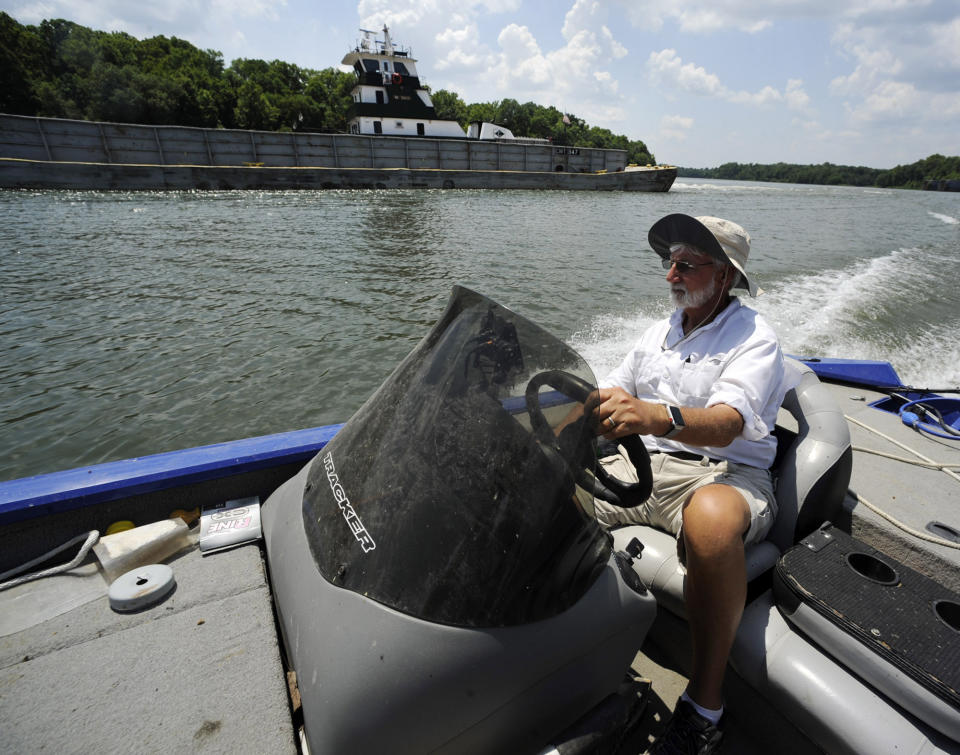 In this Tuesday, July 9, 2019 photo, Fred Hansard drives a boat past a tugboat and barge on the Tennessee-Tombigbee Waterway at Demopolis, Ala. Hansard, president of the Demopolis Yacht Basin, is frustrated with uneven development along the 234-mile waterway, which was supposed to be a catalyst for commerce that would transform a poor region when it opened in 1985. (AP Photo/Jay Reeves)