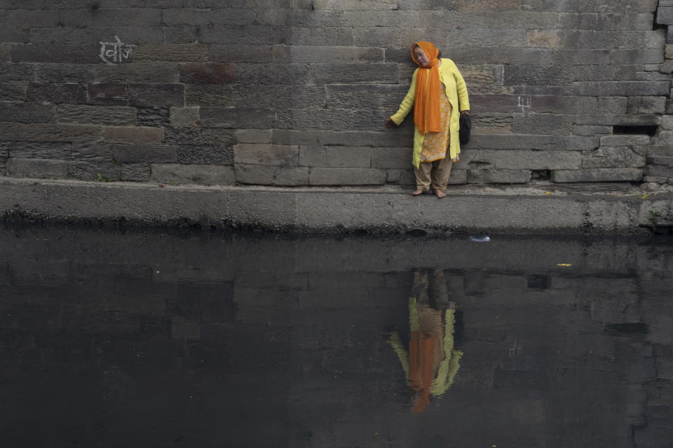A Nepalese devotee makes her way back through a narrow ledge after offering prayers in front of an idol of Astamatrika, or eight mother goddesses, on the banks of the Bagmati river in Kathmandu, Nepal, Wednesday, May 8, 2024. Devout Hindus in Nepal are performing rituals on Wednesday to mark Matatirtha Aunshi or Mother's Day. (AP Photo/Niranjan Shrestha)