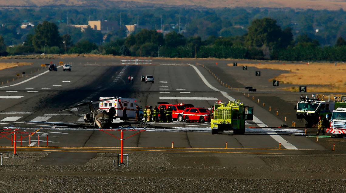 The charred remains of a privately owned small jet airplane rests on a runway surrounded by emergency vehicles on Sept. 20, 2022 at the Tri-Cities Airport in Pasco.