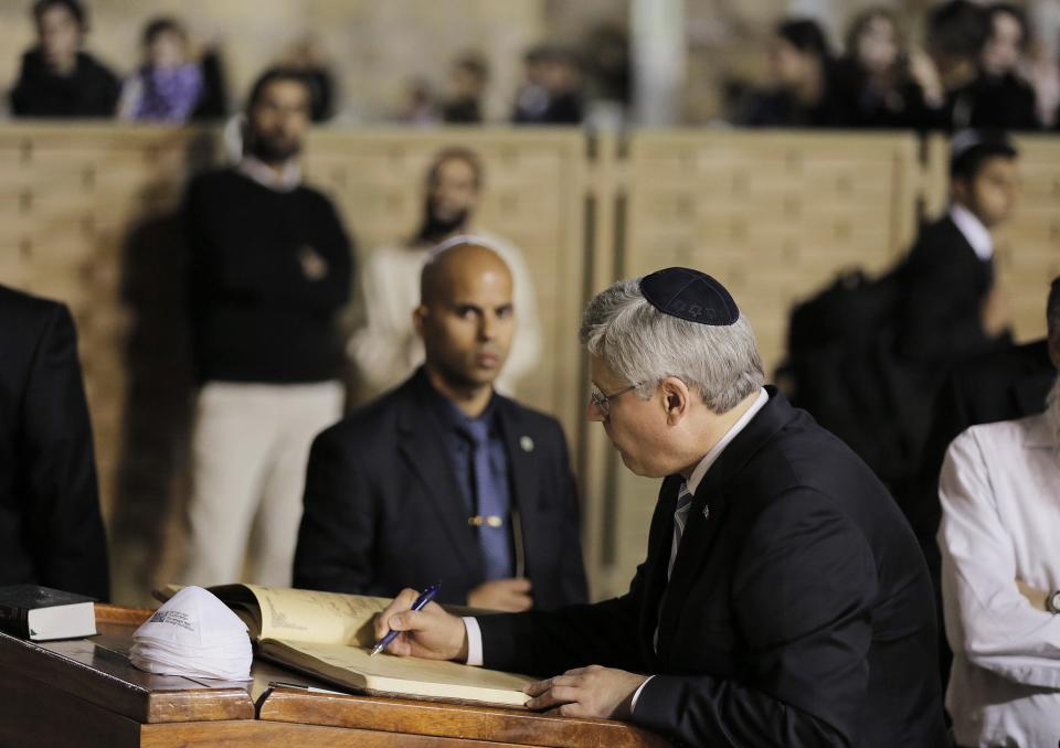 Canada's PM Harper writes in a visitor's book during his visit to the Western Wall in Jerusalem's Old City