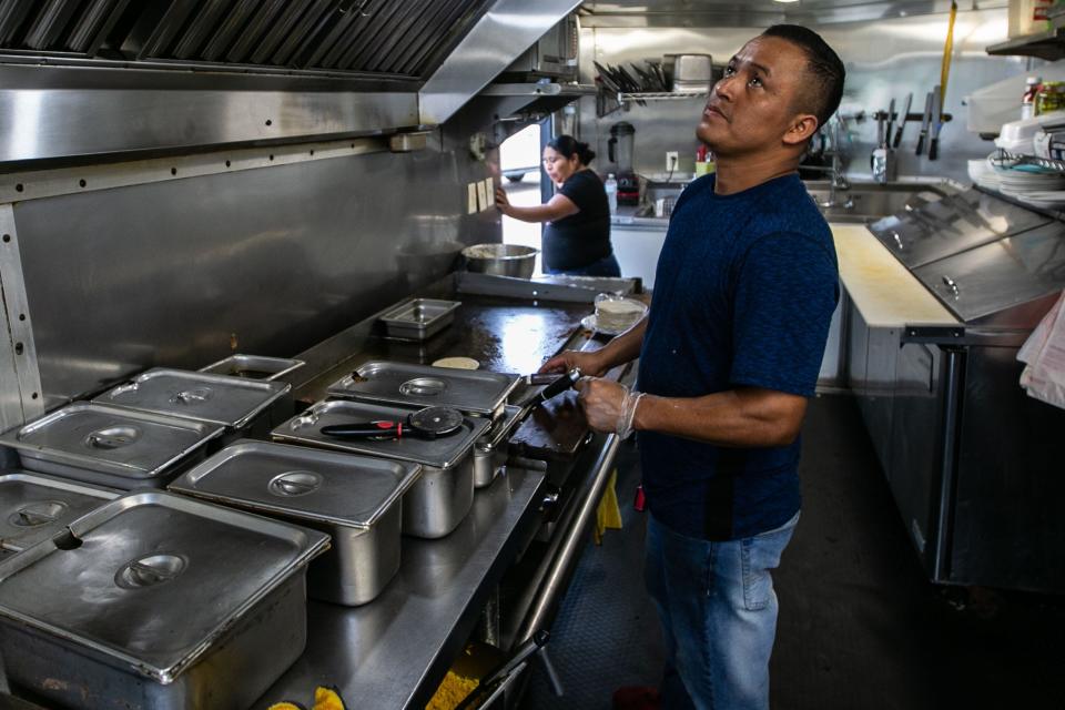 Andres Mendez makes tacos for a customer while working in the Chile & Chili's Taqueria food truck on Tennessee Street on Wednesday, May 31, 2023.