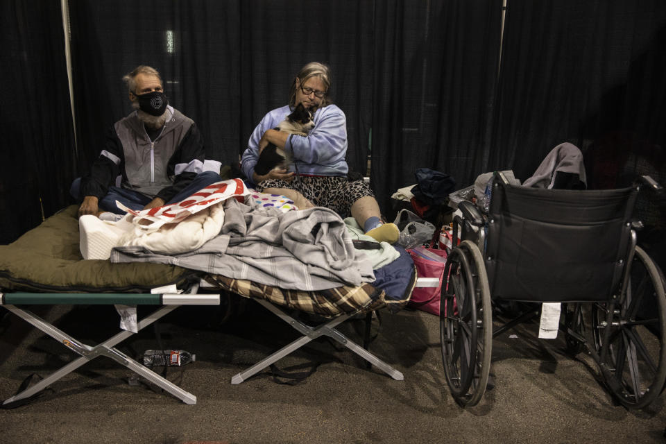 Don and Carrie Rascal from Phoenix rest on a cot with their dog at the evacuation center set up at the Jackson County Fairgrounds on Saturday, Sept. 12, 2020 in Central Point, Ore. They lost their home to the destructive wildfires devastating the region. (AP Photo/Paula Bronstein)