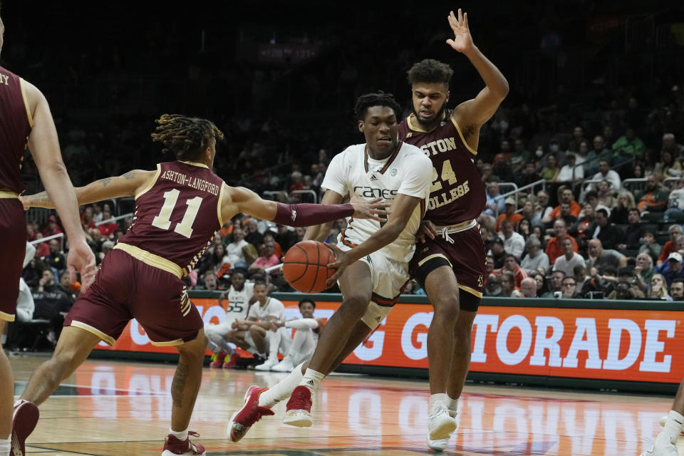 Miami forward Anthony Walker (1) drives to the basket as Boston College guard Makai Ashton-Langford (11) and forward CJ Penha Jr. (24) defend during the first half of an NCAA college basketball game, Wednesday, Jan. 11, 2023, in Coral Gables, Fla. (AP Photo/Marta Lavandier)