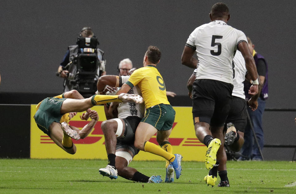 Australia's Reece Hodge, left, flies as he is pushed away by Fiji's Peceli Yato during the Rugby World Cup Pool D game at Sapporo Dome between Australia and Fiji in Sapporo, Japan, Saturday, Sept. 21, 2019. (AP Photo/Aaron Favila)