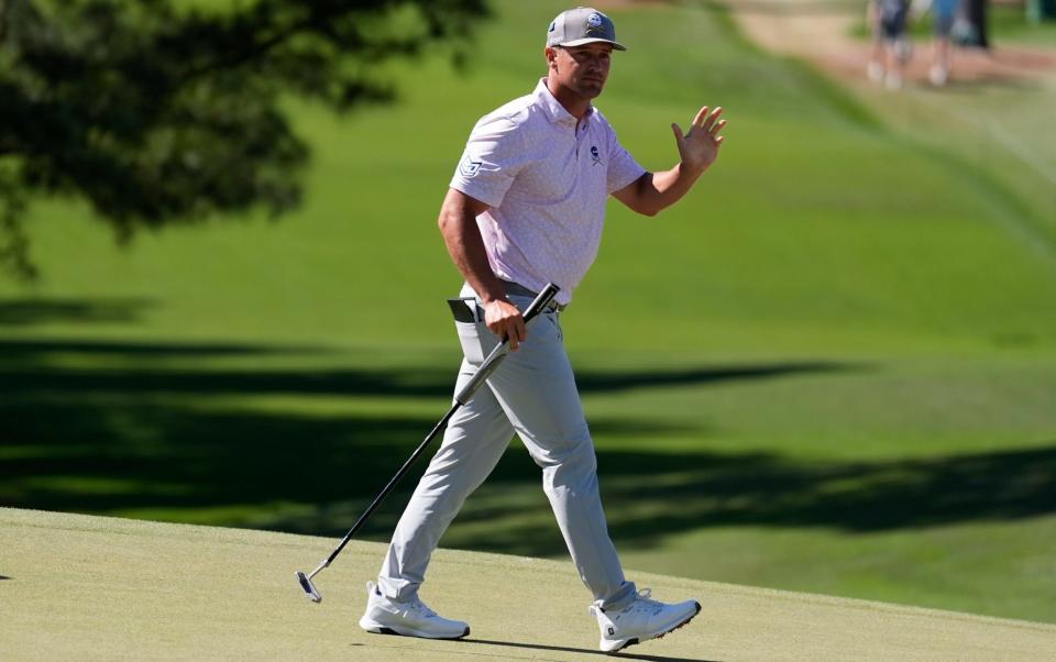 Bryson DeChambeau waves to the crowd on the seventh