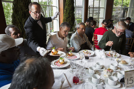 A waiter serves dessert to a table of men listening to Chinese millionaire Chen Guangbiao during a lunch he sponsored for hundreds of needy New Yorkers at Loeb Boathouse in New York's Central Park June 25, 2014. REUTERS/Lucas Jackson