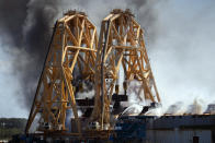 Firefighters working from the towering crane being used to dismantle the ship, hose down a fire in the overturned cargo ship Golden Ray, Friday, May 14, 2021, Brunswick, Ga. The Golden Ray had roughly 4,200 vehicles in its cargo decks when it capsized off St. Simons Island on Sept. 8, 2019. Coast Guard Petty Officer 2nd Class Michael Himes says there have been no injuries and all demolition crew members were safely evacuated. (AP Photo/Stephen B. Morton)