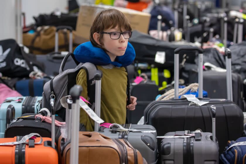 Los Angeles, CA - December 28: Greyson Salazar, 9, arriving from Dallas, searches for his luggage among the sea of bags accumulated at baggage claim at LAX Southwest Terminal 1 on Wednesday, Dec. 28, 2022 in Los Angeles, CA. (Irfan Khan / Los Angeles Times)