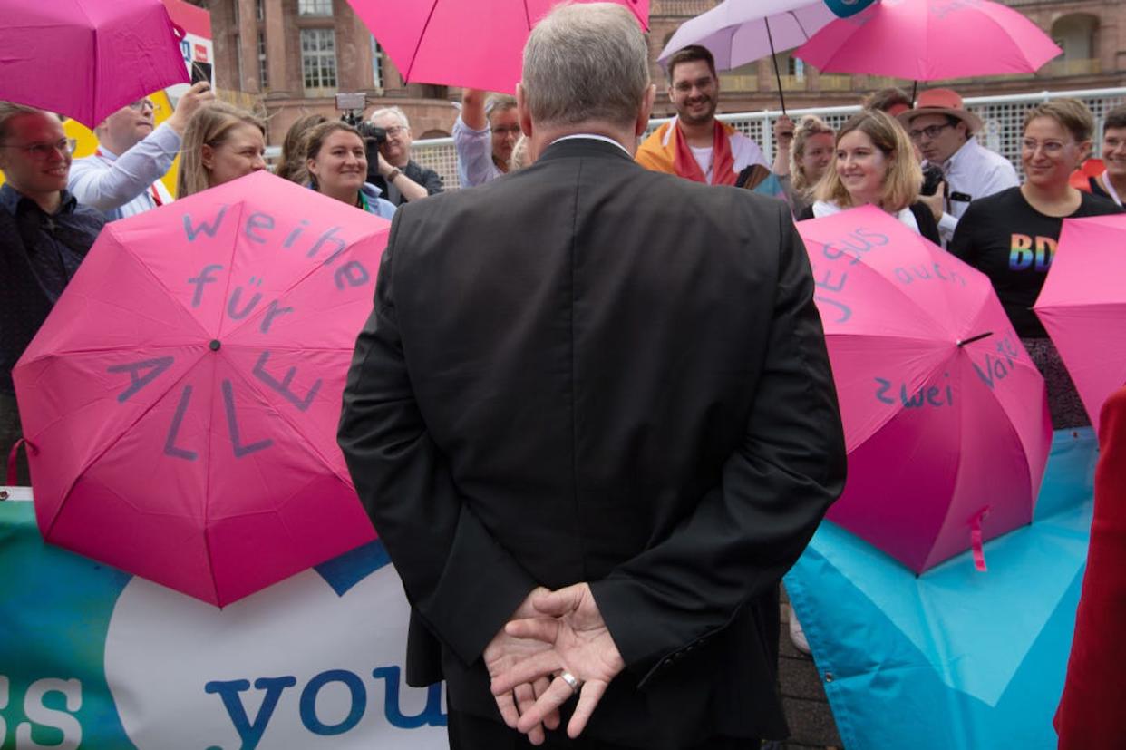 German Bishop Georg Bätzing talks with members of various Catholic youth organizations holding up umbrellas reading "Consecration for All" and "Jesus had two fathers." <a href="https://www.gettyimages.com/detail/news-photo/september-2022-hessen-frankfurt-main-bishop-georg-b%C3%A4tzing-news-photo/1243041607?adppopup=true" rel="nofollow noopener" target="_blank" data-ylk="slk:Sebastian Gollnow/Picture Alliance via Getty Images;elm:context_link;itc:0;sec:content-canvas" class="link ">Sebastian Gollnow/Picture Alliance via Getty Images</a>