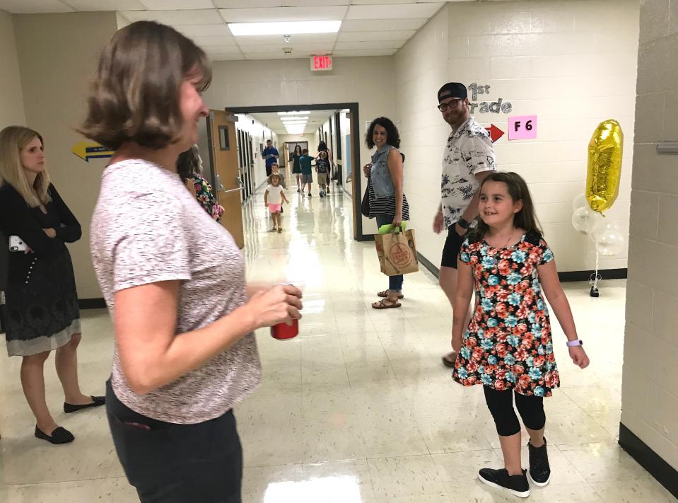 Third grade student Eliza Reedy (right) heads to her new classroom for a tour with her parents, Josh and Rachel, after hugging school counselor Melissa McNabb (left).