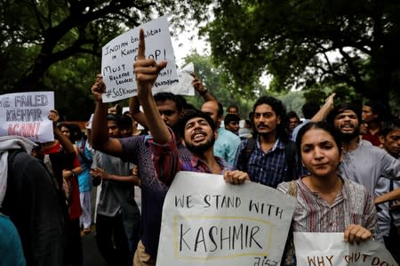 People hold signs and shout slogans during a protest after the government scrapped the special status for Kashmir, in New Delhi