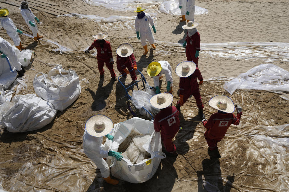 Workers carry out a cleanup operation on Mae Ramphueng Beach after a pipeline oil spill off the coast of Rayong province in eastern Thailand, Sunday, Jan. 30, 2022. Some 20-50 tons of oil are estimated to have leaked Tuesday night in the Gulf of Thailand from an undersea hose used to load tankers at an offshore mooring point owned by the Star Petroleum Refining Co. (AP Photo/Sakchai Lalit)