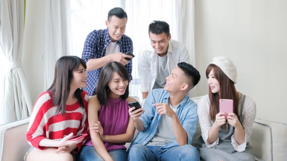 A group of young people use their smartphones.