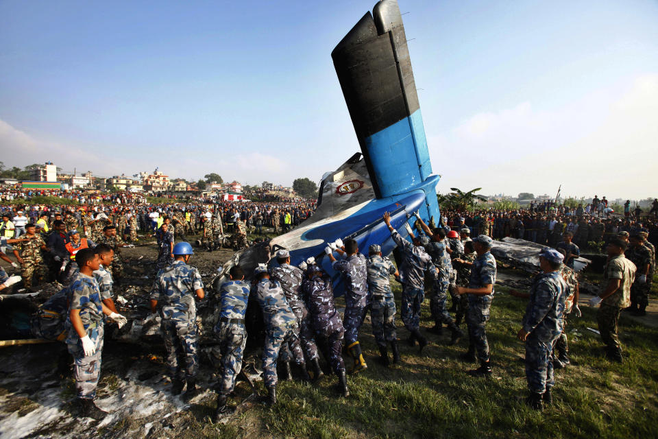 Nepalese police search move the remains of a Sita Air airplane at the crash site near Katmandu, Nepal, early Friday, Sept. 28, 2012.  The plane carrying trekkers into the Everest region crashed just after takeoff Friday morning in Nepal's capital, killing all 19 people on board, authorities said. (AP Photo/Niranjan Shrestha)