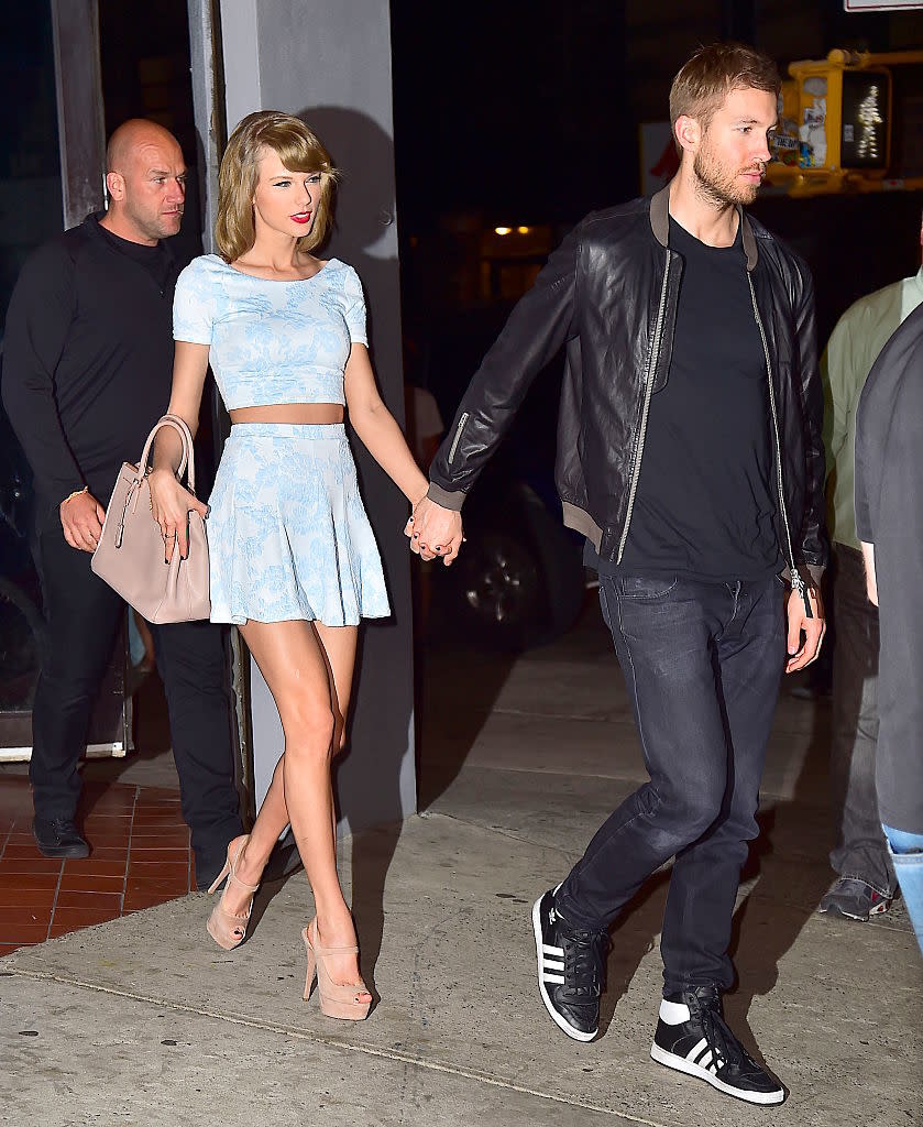 Taylor Swift in a stylish two-piece outfit holds hands with Calvin Harris, who is wearing a leather jacket and jeans, on a night out