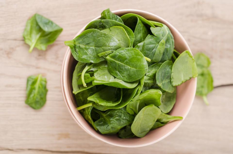 bowl of fresh spinach leaves on wood