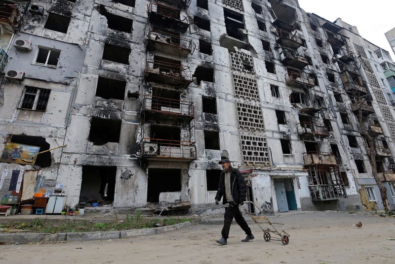 A local resident walks past a damaged apartment building in Mariupol