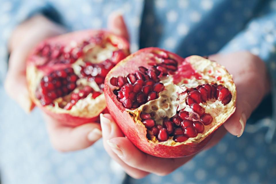 woman holding pomegranate halves