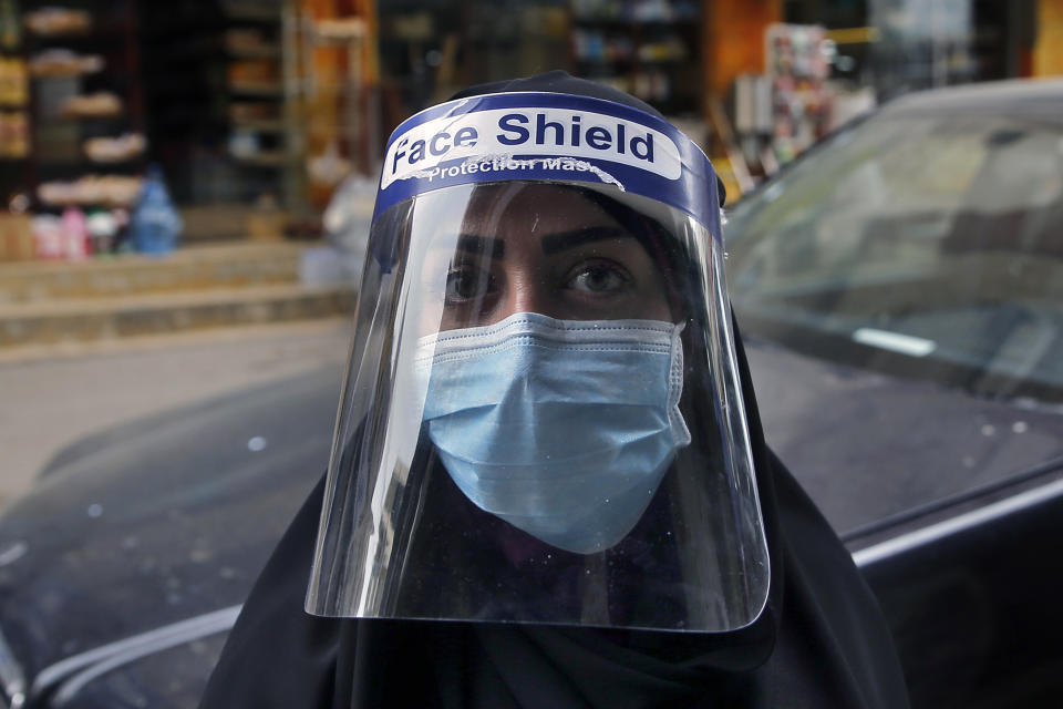 A woman poses for a photograph, as she wears a face shield to help protect herself from the coronavirus outbreak, in the southern suburb of Beirut, Lebanon, Friday, March 27, 2020. The virus causes mild or moderate symptoms for most people, but for some, especially older adults and people with existing health problems, it can cause more severe illness or death. (AP Photo/Bilal Hussein)