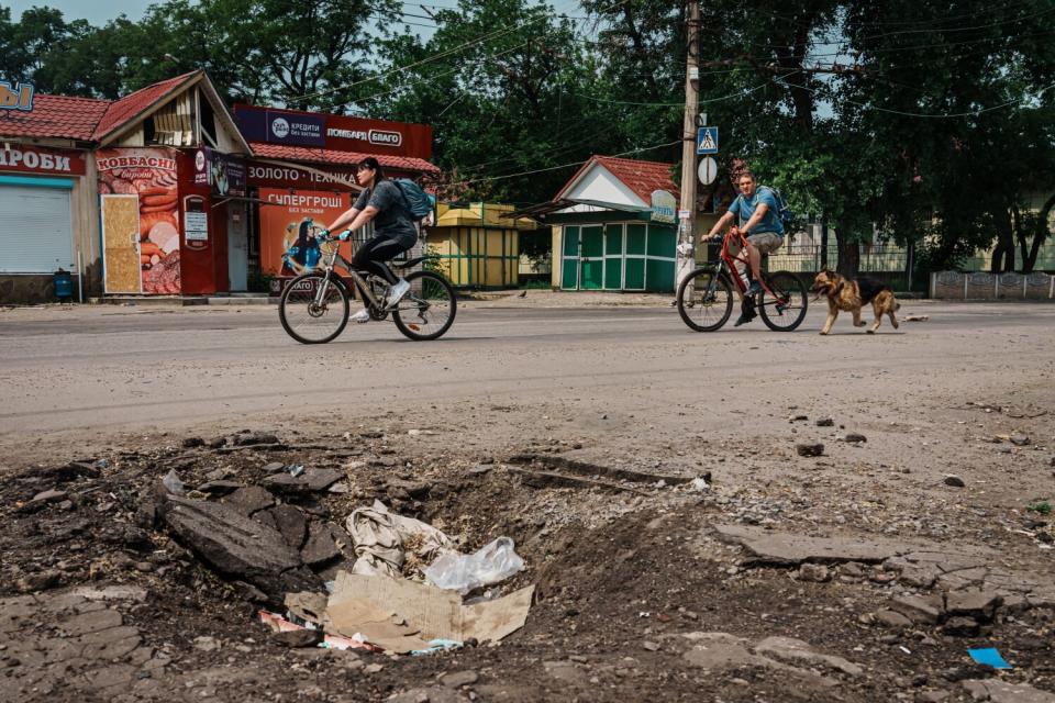 People ride bikes on a torn-up street