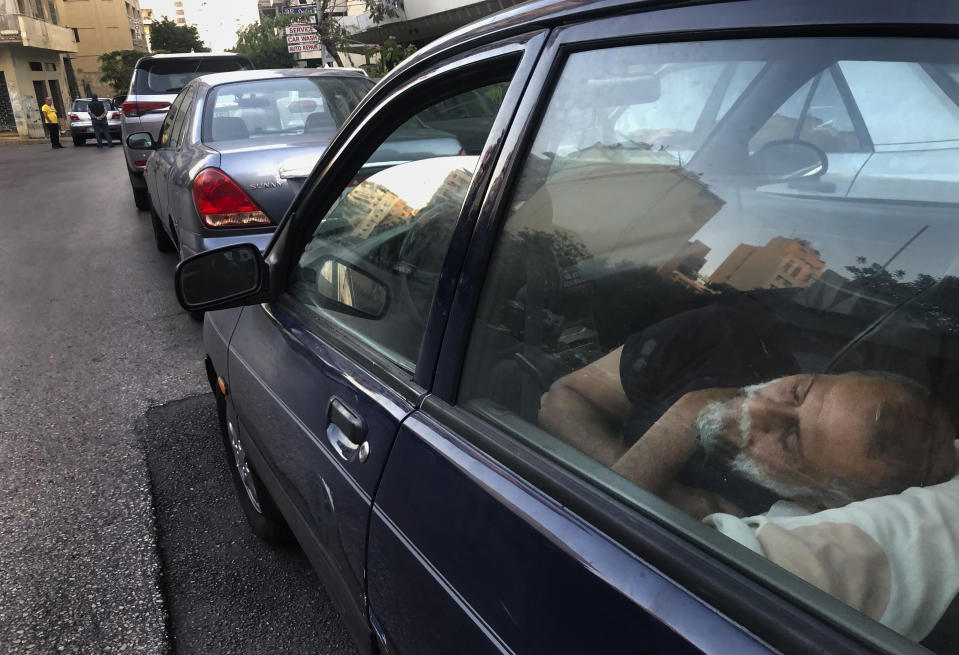 FILE - In this June 12, 2021 file photo, a taxi driver sleeps in the early morning inside his car as he waits in a long queue for gasoline in the Lebanese capital, Beirut. Lebanon is struggling amid a 20-month-old economic and financial crisis that has led to shortages of fuel and basic goods like baby formula, medicine and spare parts. The crisis is rooted in decades of corruption and mismanagement by a post-civil war political class. (AP Photo/Hussein Malla, File)