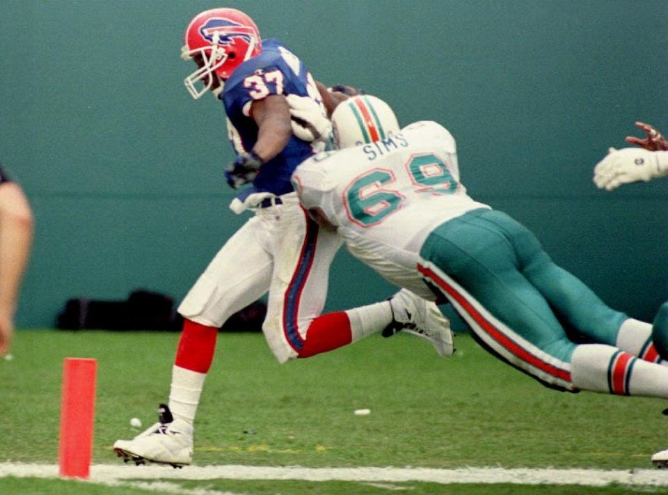 Buffalo Bills defensive back Nate Odomes (L) evades a diving tackle by Miami Dolphins offensive guard Keith Sims to score a touchdown on Dec. 19, 1993 in Miami, Florida, after Odomes intercepted a Dolphins pass.  Buffalo scored 21 points in the quarter on turnovers.