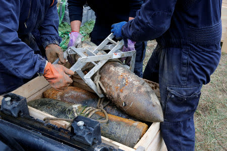 Deminers from a bomb-disposal unit place in a box an unexploded shell recovered in the Meuse River at Sivry-sur-Meuse, close to WWI battlefields, near Verdun, France, October 24, 2018 before the centenial commemoration of the First World War Armistice Day. REUTERS/Pascal Rossignol