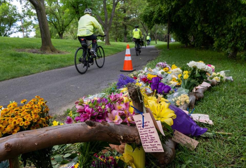 A cyclist rides past a memorial of flowers on Wednesday, May 3, 2023, marking the location that Karim Abou Najm, a graduating senior at UC Davis, was stabbed Saturday in Sycamore Park in Davis. It was the second of three stabbings - two fatal - in the city in less than a week.