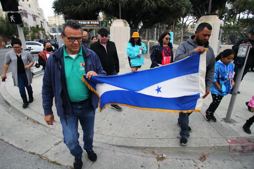 A group of people from Central America and Mexico, hold the Honduras flag as they walk to MacArthur Park to demonstrate and have a vigil in memory of the 38 people who were killed in a fire that broke out at the National Migration Institute Facility along the U.S.-Mexico border in Ciudad Juarez, Mexico, the demonstration took park in MacArthur Park in Los Angeles on Friday, March 31, 2023. (Photo by James Carbone For Los Angeles Times Espanol)