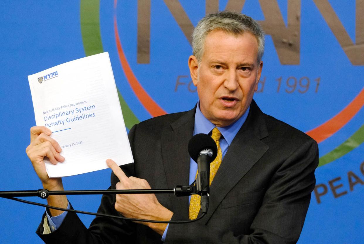 Mayor Bill De Blasio holds a copy of the NYPD Disciplinary System Penalty Guidelines. 