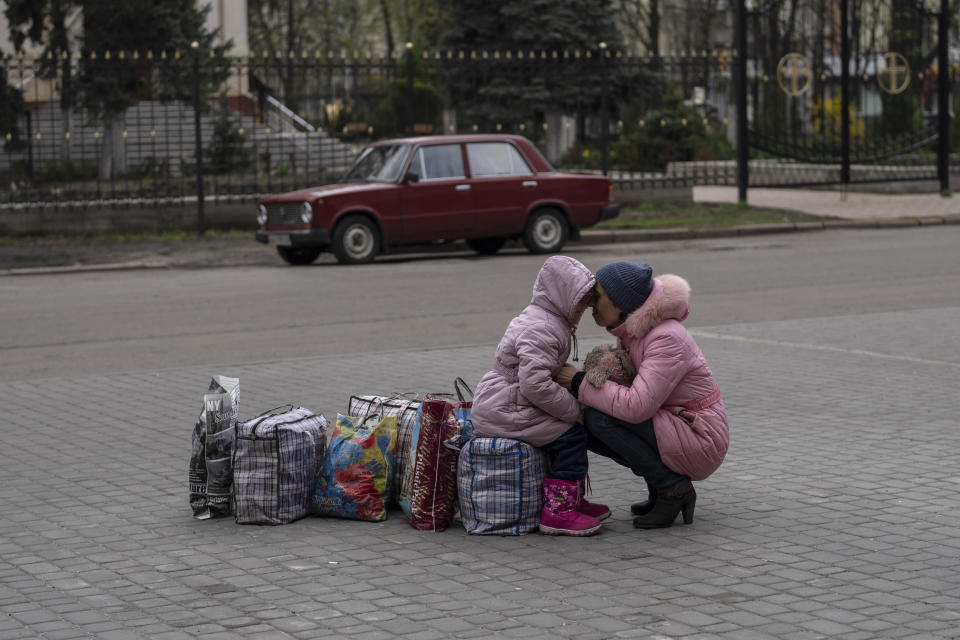 A mother hugs her daughter as they wait for a bus to flee from Sloviansk city, in Donetsk district, to travel to Rivne , western Ukraine, on Saturday, April 16, 2022. (AP Photo/Petros Giannakouris)